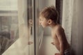 Little kid is looking out the window. Image with selective focus and toning Royalty Free Stock Photo