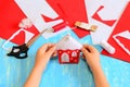 Little kid made a Christmas tree house ornament of red and white felt. Child holds Christmas house ornament in his hands