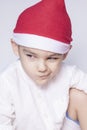 A little kid making a funny annoyed face. Annoyed Christmas Boy in Santa Hat. A really serious and handsome kid