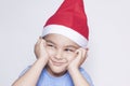 A little kid making funny annoyed face. Annoyed Christmas Boy in Santa Hat Royalty Free Stock Photo