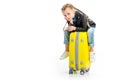 Little kid with pigtails holding hand on chin and sitting on wheel suitcase