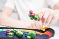 Little kid play toy sitting at table closeup. Hand of child magnetize and pick up colorful metal playthings from plate.