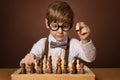 Little Kid playing Chess Game. Intelligent Small Boy in Eyeglasses next to Chessboard. Child Education and Development Royalty Free Stock Photo