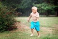 Little kid playing with water on hot summer day. Boy with garden sprinkler. Boy runs on a field under water drops Royalty Free Stock Photo