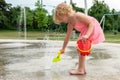 Little kid playing at water splash pad in the public park playground during hot summer day Royalty Free Stock Photo