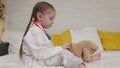 little kid plays with teddy bear sitting on bed in hospital, childhood dream of becoming doctor, kid veterinarian Royalty Free Stock Photo