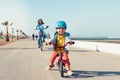 Little kid riding a balance bike with his mother on a bicycle