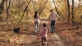 little kid runs catching up with mother and father, happy family, active children outdoor games autumn, cheerful joyful