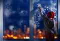 Boy decorate window for New Year with snowflake Royalty Free Stock Photo