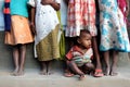 A little kid sat on muddy floor with their sisters.