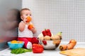 A little kid sits surrounded by fruits and vegetables, holding tomatoes in his hands. The concept of vegetarianism, diet and Royalty Free Stock Photo