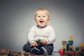 Giggling child sitiing on the floor with toys. Royalty Free Stock Photo