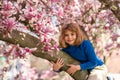 Little kid smelling spring flower outdoor. Portrait of smiling child face near blossom spring flowers. Kid among Royalty Free Stock Photo