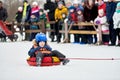 Little kid on snow tubing with sled dog