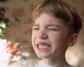 Little kid with tears on his face close-up. boy tries to pull out his baby tooth with thread