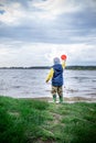 Little kid throwing rocks in lake. rubber boots Royalty Free Stock Photo