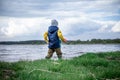 little kid throwing rocks in lake. rubber boots Royalty Free Stock Photo