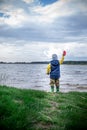 little kid throwing rocks in lake. rubber boots Royalty Free Stock Photo