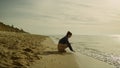 Little kid touching sea waves on sunset beach. Cute girl playing sand at ocean. Royalty Free Stock Photo