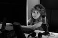 Little kid using desktop pc by night, child boy illuminated by the blue light of a computer screen. Gamer play desktop