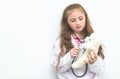 Little kid using Doctor suit and equipment to check Teddy bea Royalty Free Stock Photo