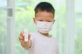 Little kid wearing medical face mask holding Rapid Antigen Test kit with Positive result at home