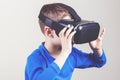 Little kid wearing virtual reality goggles watching movies or playing video games Royalty Free Stock Photo