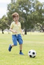 Little kid 7 or 8 years old enjoying happy playing football soccer at grass city park field running and kicking the ball excited i Royalty Free Stock Photo