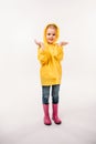 little kid in yellow raincoat and rubber boots