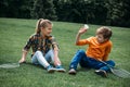 Little kids with badminton rackets and shuttlecock sitting on the grass at park Royalty Free Stock Photo