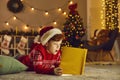 Little boy opens magic book and reads wonderful stories and fairy tales on Christmas Eve at home