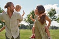 Little kids, boy and girl giving each other high five while enjoying piggyback ride on the back of their mom and dad Royalty Free Stock Photo