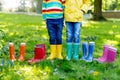 Little kids, boys or girls in jeans and yellow jacket in colorful rain boots