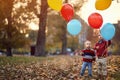 Kids brothers playing together on the autumn park with balloons