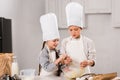 little kids in chef hats and aprons whisking eggs in bowl at table Royalty Free Stock Photo