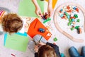 Little kids and educator folding lego and drawing with colored pencils sitting on floor in playroom top view