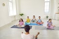 Little kids girls with their woman couch practicing yoga sitting in gym in Lotus pose. Royalty Free Stock Photo