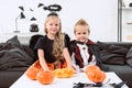 little kids in halloween costumes sitting on sofa at table with pumpkins Royalty Free Stock Photo