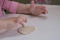 Little kids hands touching a round piece of dough in process of preparing food