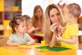 Little kids molded from clay toys. Teacher plays with children.