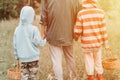 Little kids mushroom pickers go to the forest by the hand with their grandmother. family of survivalists gathers a wild fungus har Royalty Free Stock Photo