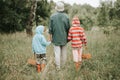 Little kids mushroom pickers go to the forest or woodland by the hand with their grandmother. family of survivalists gathers a wil Royalty Free Stock Photo