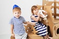 Little kids playing with cardboard ship on white background. Hap Royalty Free Stock Photo