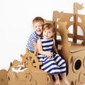 Little kids playing with cardboard ship on white background. Hap