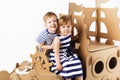 Little kids playing with cardboard ship on white background. Hap Royalty Free Stock Photo