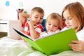 Little kids reading book in bed at home