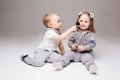 Little kids sitting, playing at studio with cosmetics, boy making makeup for pretty blonde girl with two tails. Children Royalty Free Stock Photo