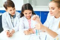 Little kids with teacher in school laboratory mixing liquids Royalty Free Stock Photo