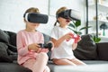 little kids in virtual reality headsets playing video game on sofa Royalty Free Stock Photo