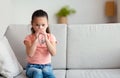 Little Korean Girl Drinking Water Sitting On Couch At Home Royalty Free Stock Photo